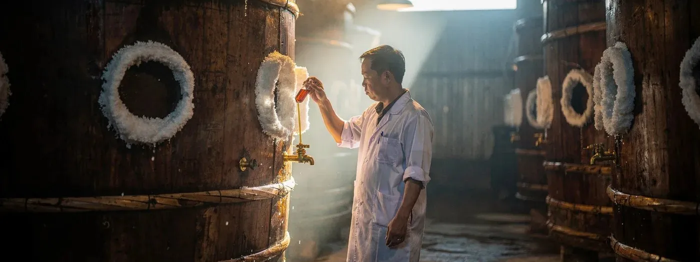 Rows of wooden fermentation vats in a fish sauce production hall